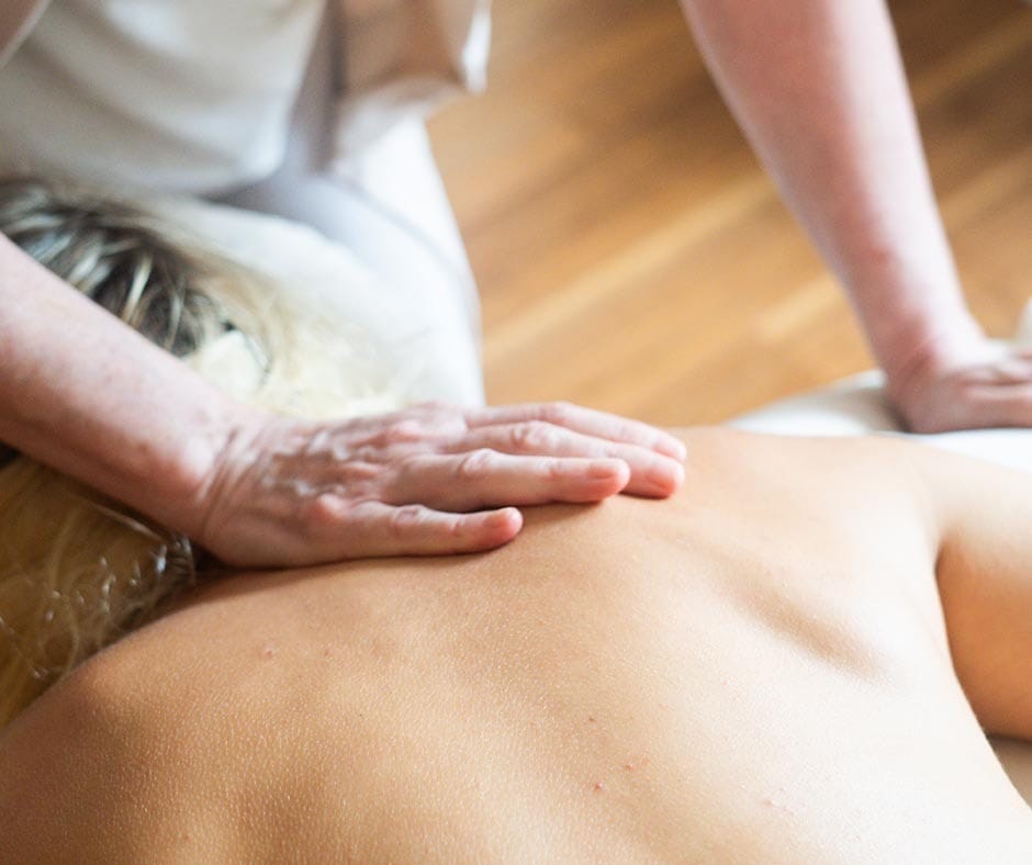 Massage therapist working on upper back and shoulder tension during a spa treatment