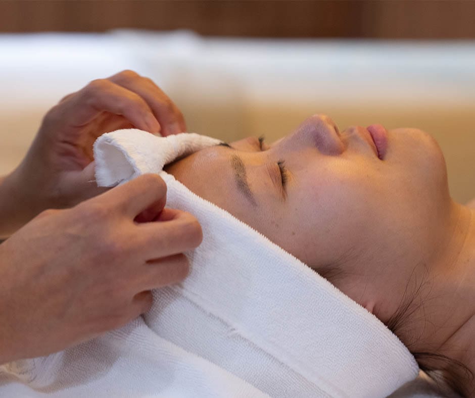 Esthetician evaluating a guest's skin before a facial at ila Only Spa in NYC